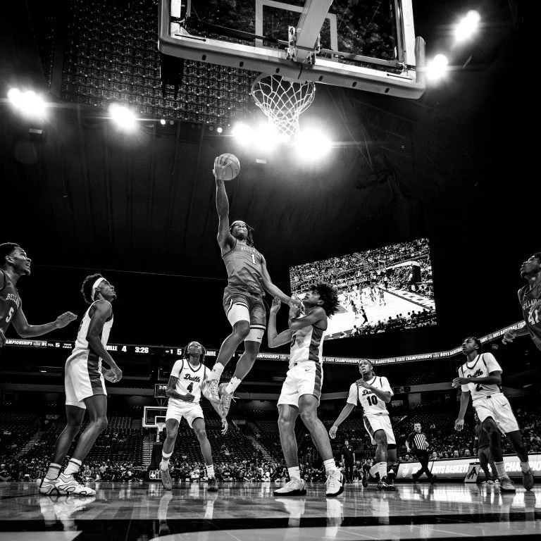A basketball game in progress with one player dunking the ball while others are watching in an arena.