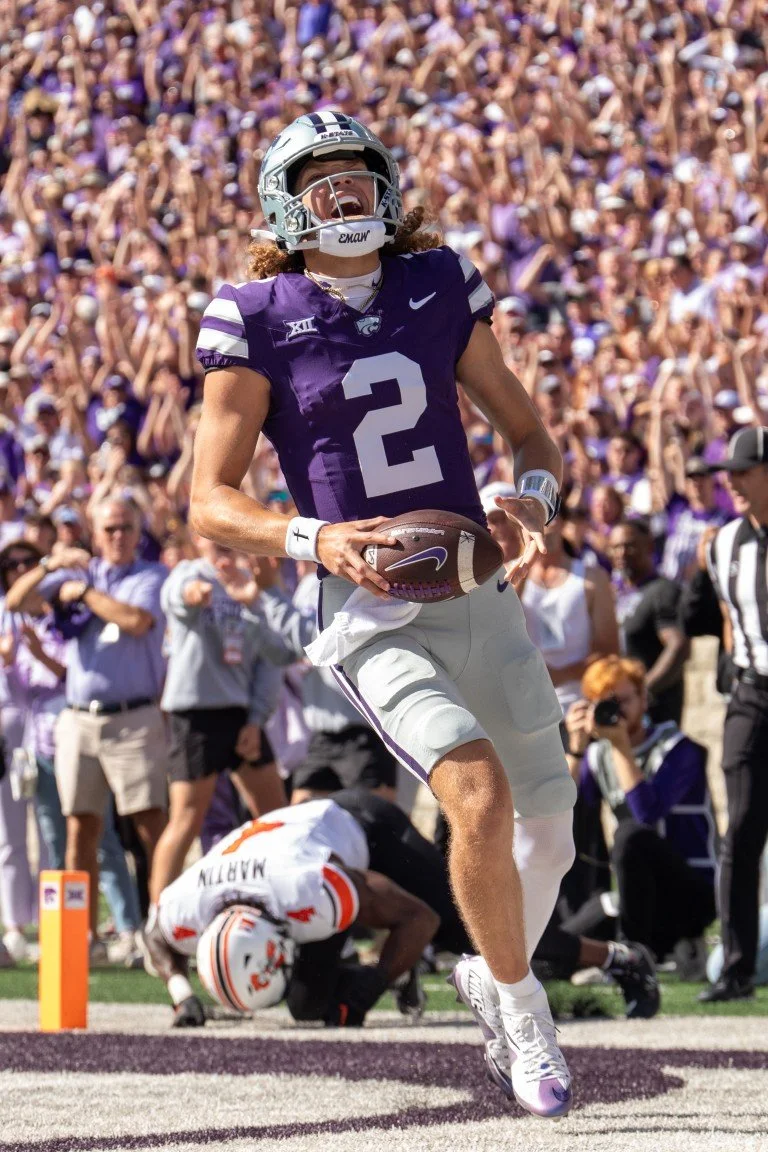 A football player wearing a purple jersey with the number 2 celebrates in front of a cheering crowd after scoring a touchdown or making a big play during a game.