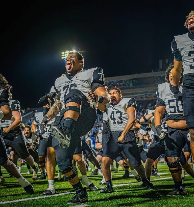 Football players celebrating on the field at night, some jumping and shouting in joy.