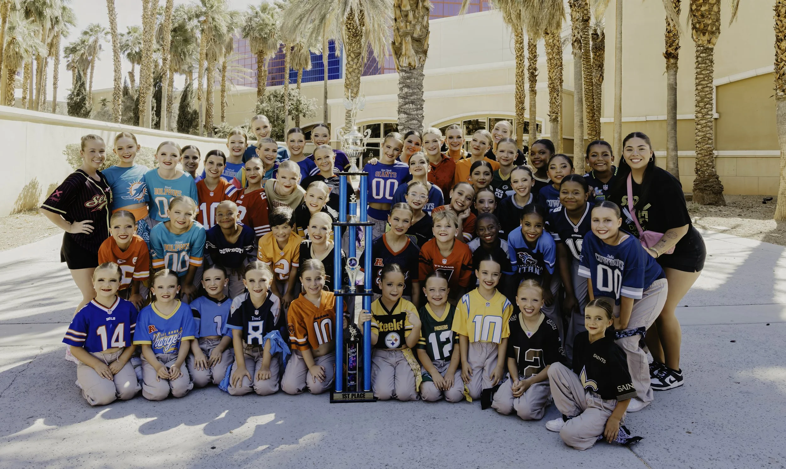 A large group of Sequel Dance Complex dancers at a national dance competition holding a trophy.
