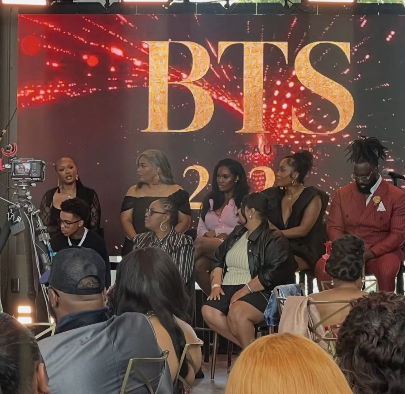 A panel of mostly women seated on stage during an event, with a large screen behind them displaying the words "BHS 2023" with fireworks graphics.