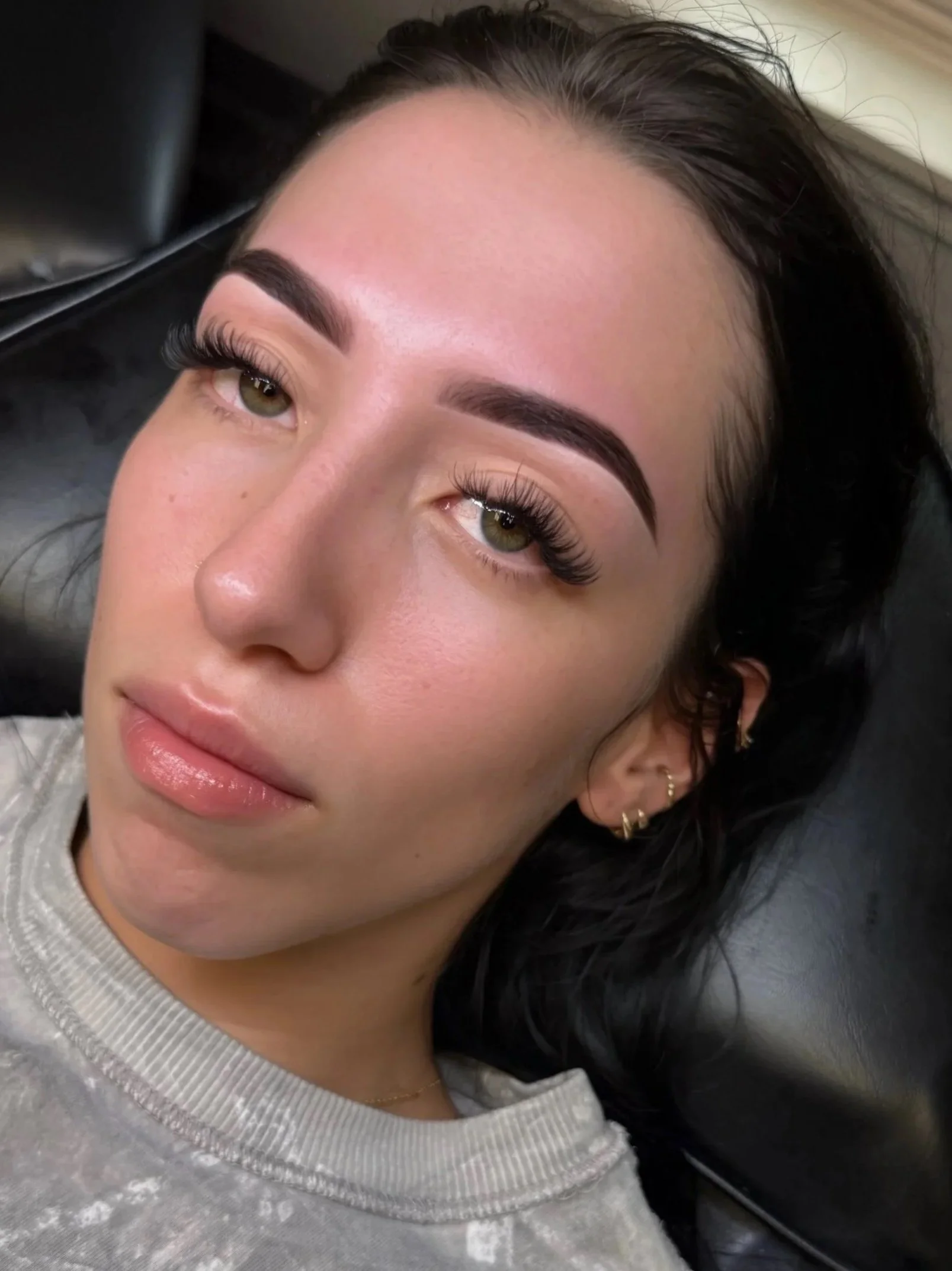 Close-up of a woman with dark hair and brown eyes, lying down and looking up.