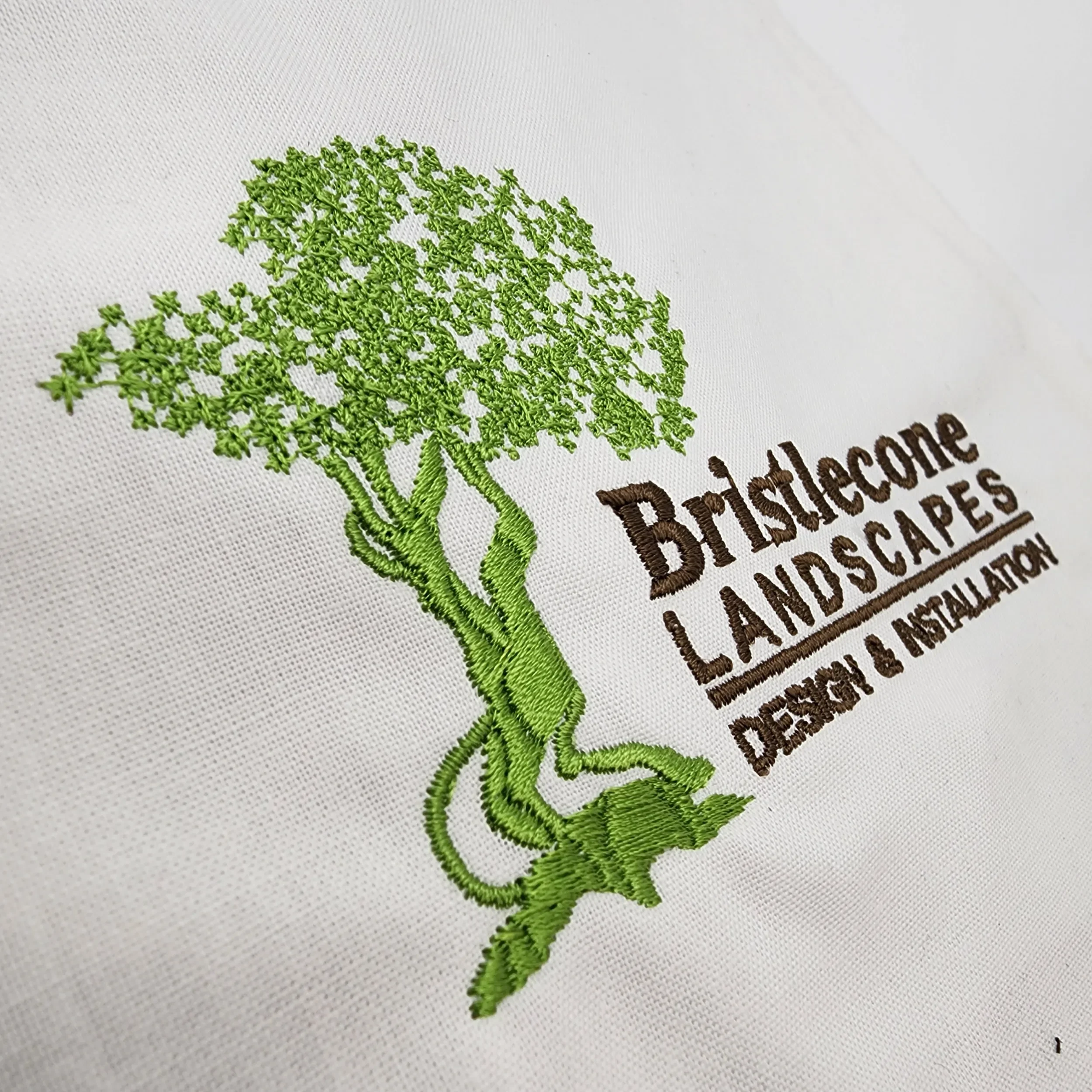 Custom hand digitized tree logo embroidery for Bristlecone Landscaping polos.