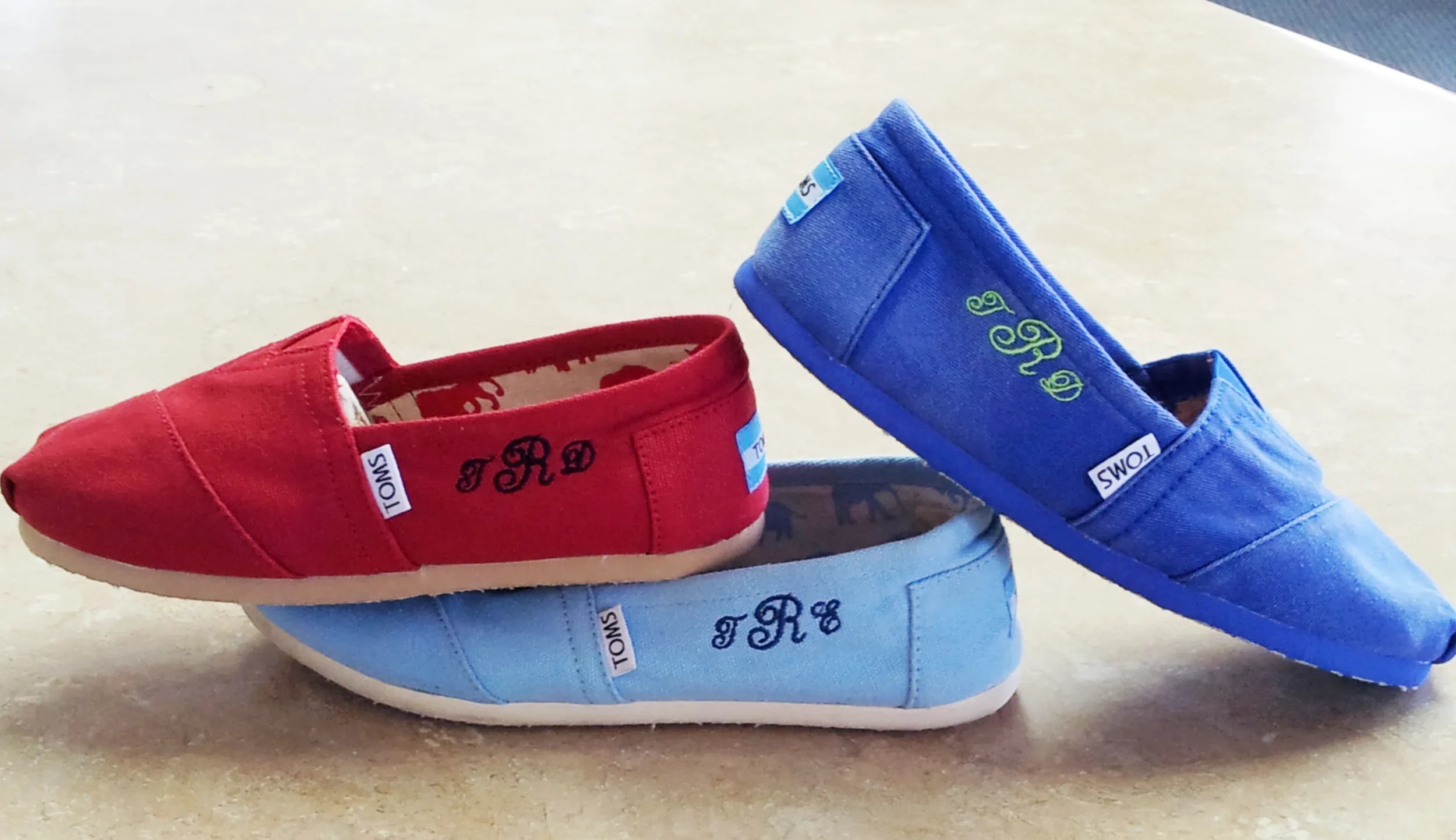 Group display of three custom hand digitized monogrammed canvas shoes in Siloam Springs, Arkansas.