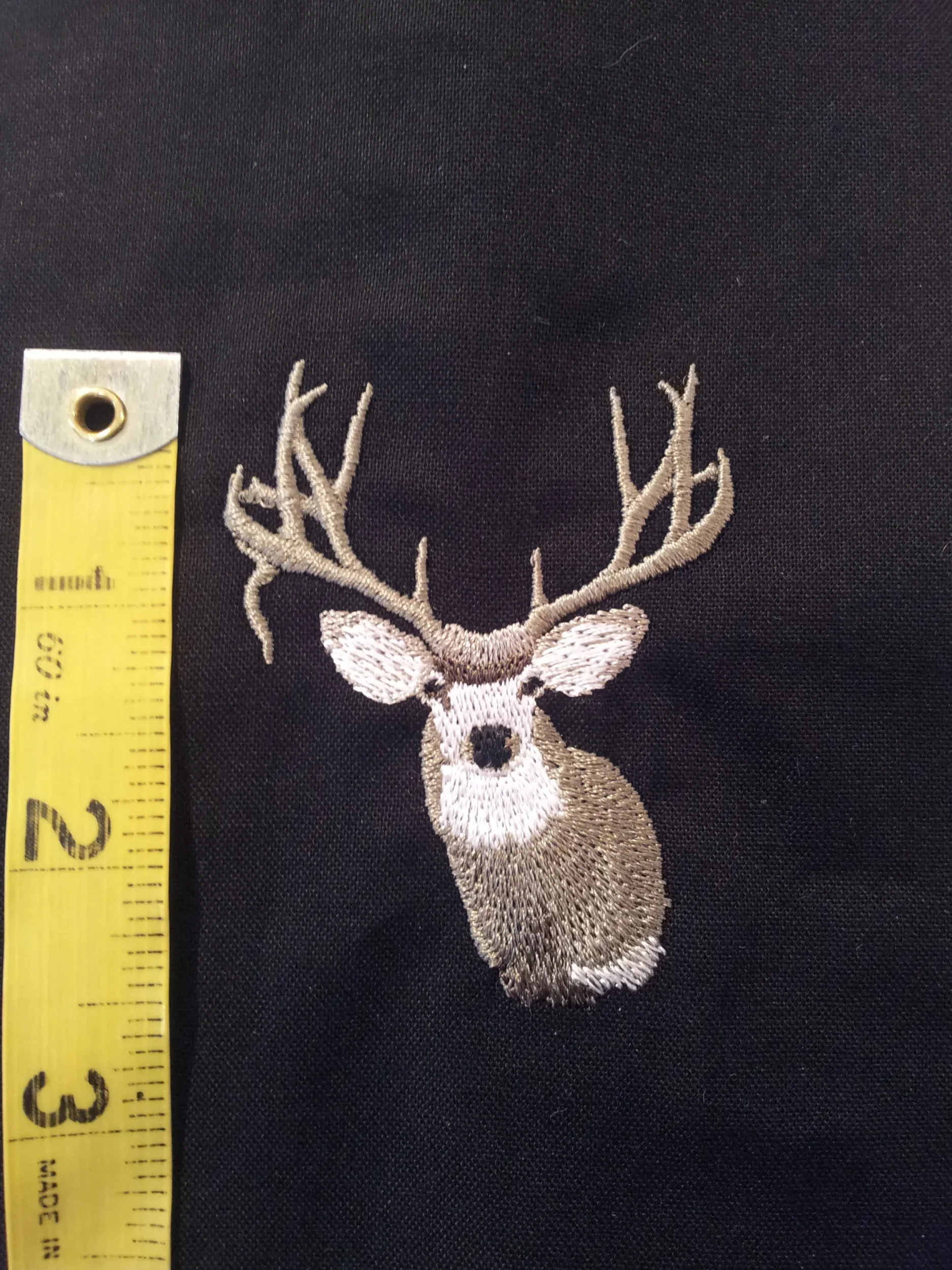 Size measurement with tape measure of hand digitized custom mule deer embroidery.