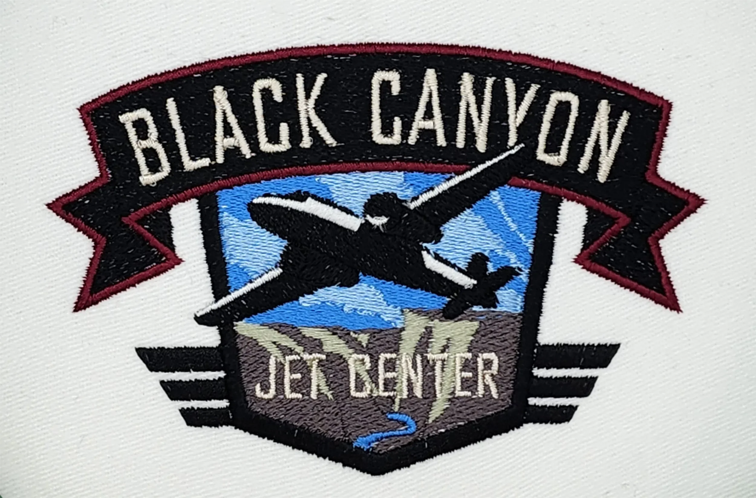Hand digitized Black Canyon Jet Center logo embroidery for caps, beanies, hoodies, and polos.