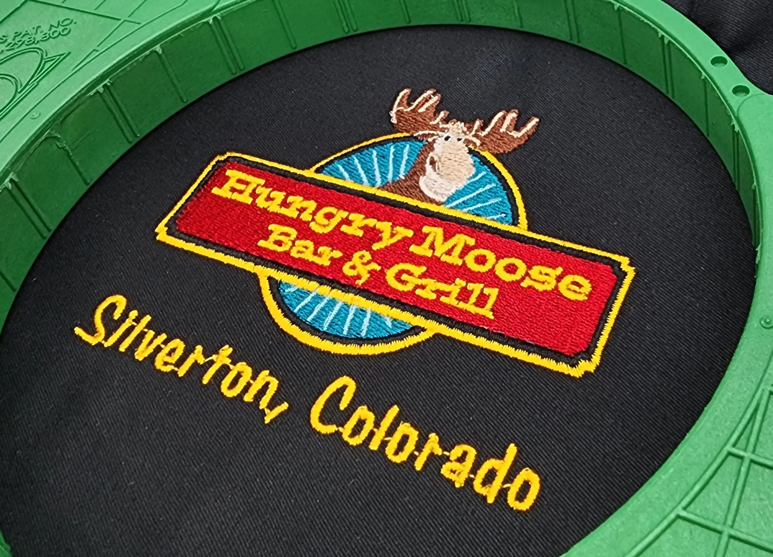 Angled view of hand digitized Hungry Moose restaurant logo embroidery for woven shirts and polos.