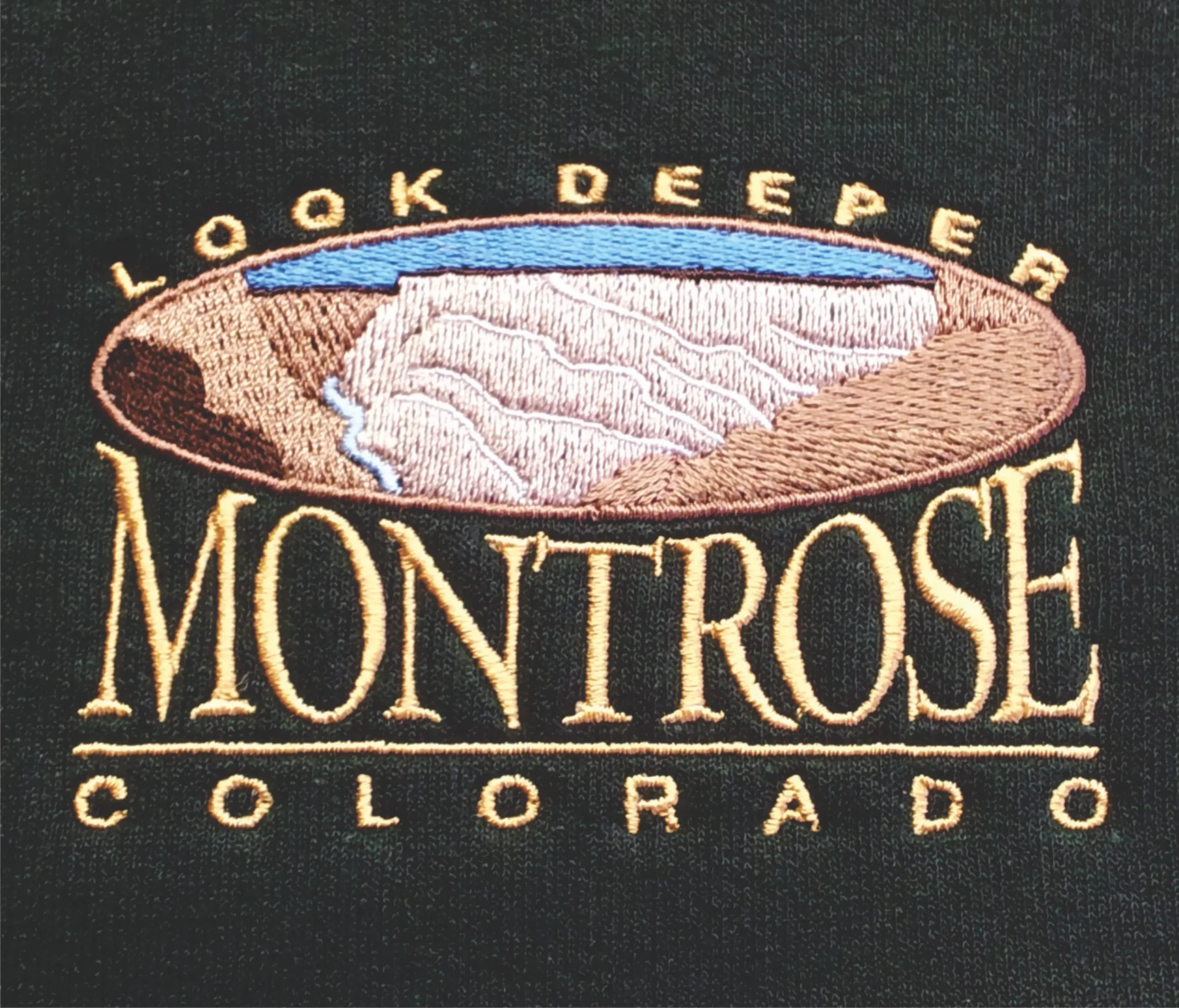 Custom hand digitized Montrose Look Deeper community logo embroidery on caps and hoodies.