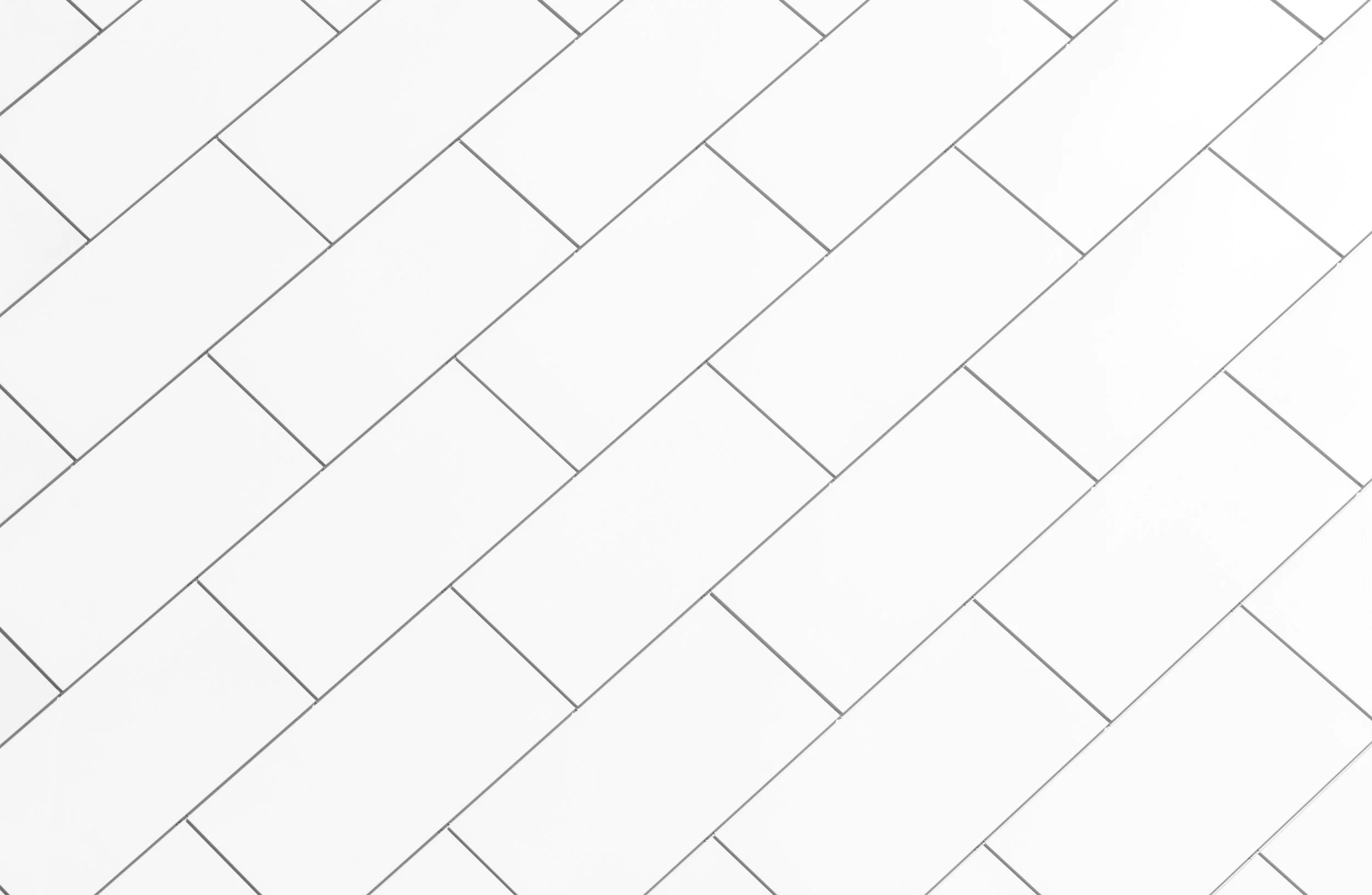 Close-up of a white brick wall with black mortar lines arranged in a diagonal pattern.