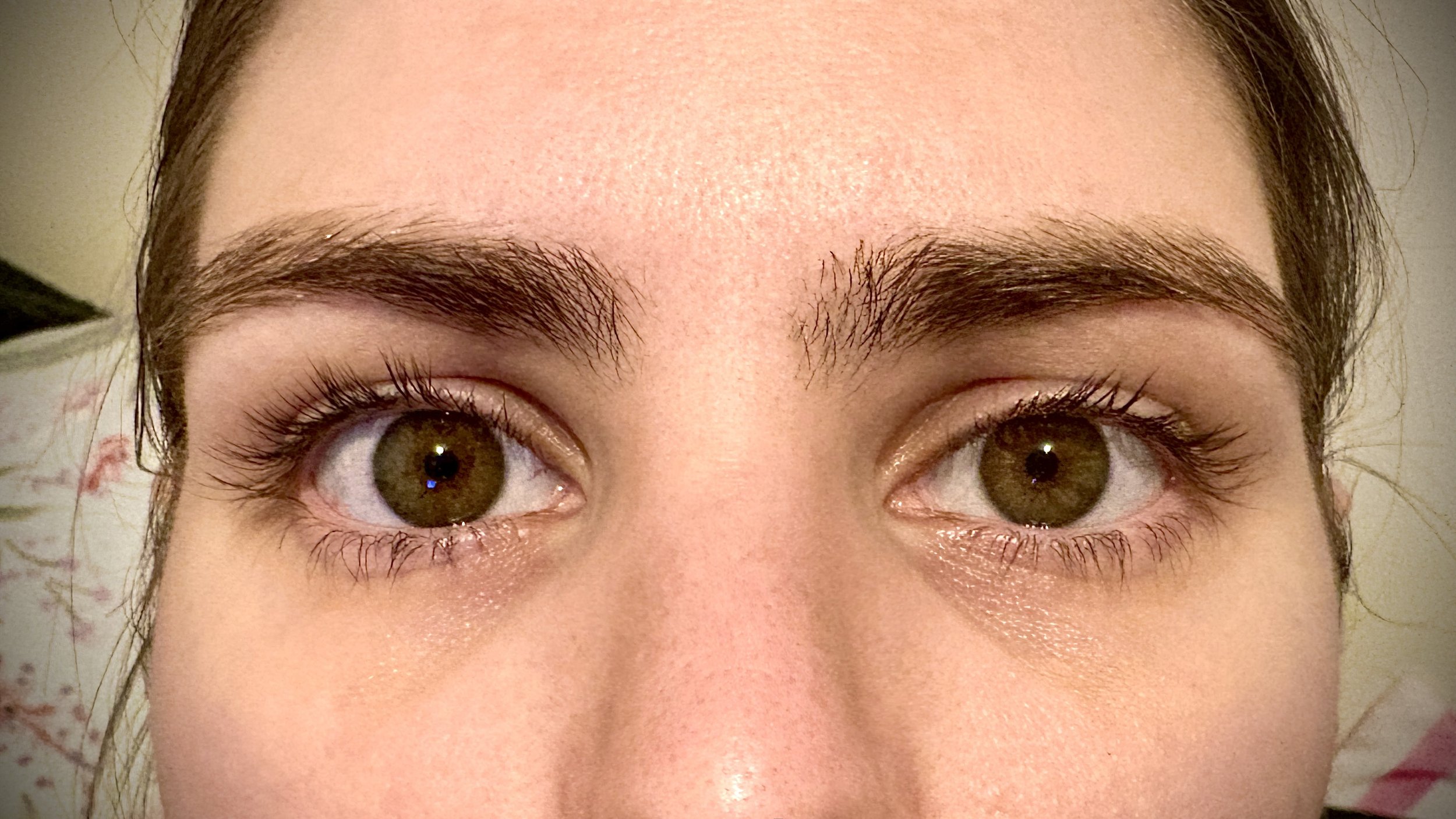 Close-up of a woman's eyes and eyebrows with clear skin and brown irises.