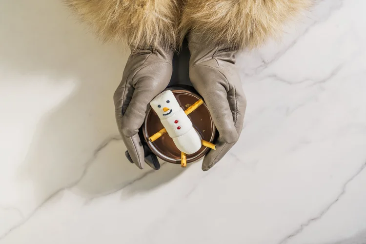 Furry winter gloves holding a cup of hot chocolate