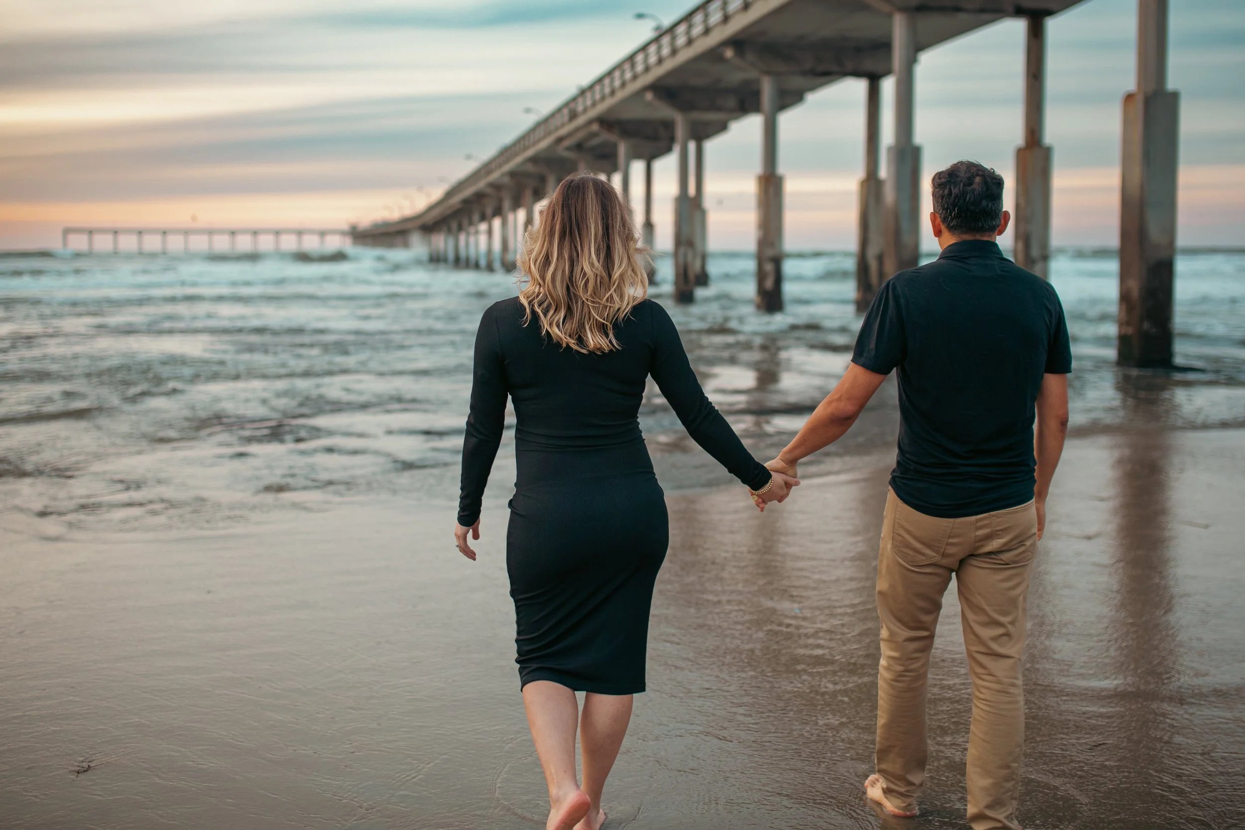 Couple walking hand in hand at sunset by the Ocean Beach pier, San Diego potrait photography