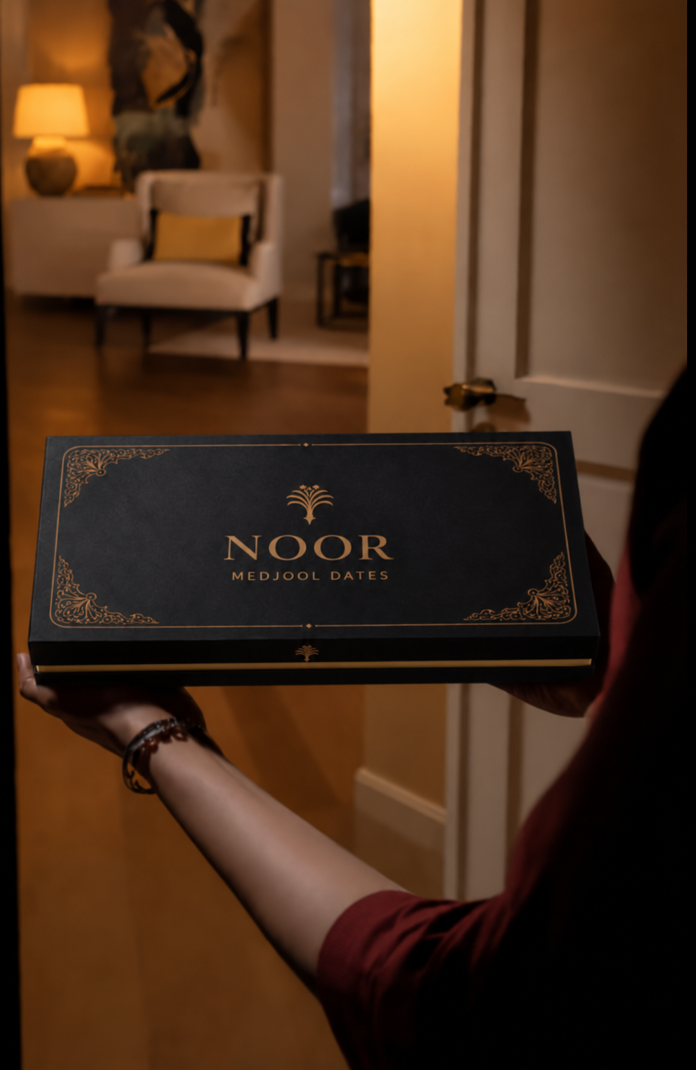 NOOR Medjool date gift box held in both hands, showing the gold middle rim
