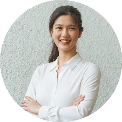 Smiling woman in white shirt standing against a textured wall.