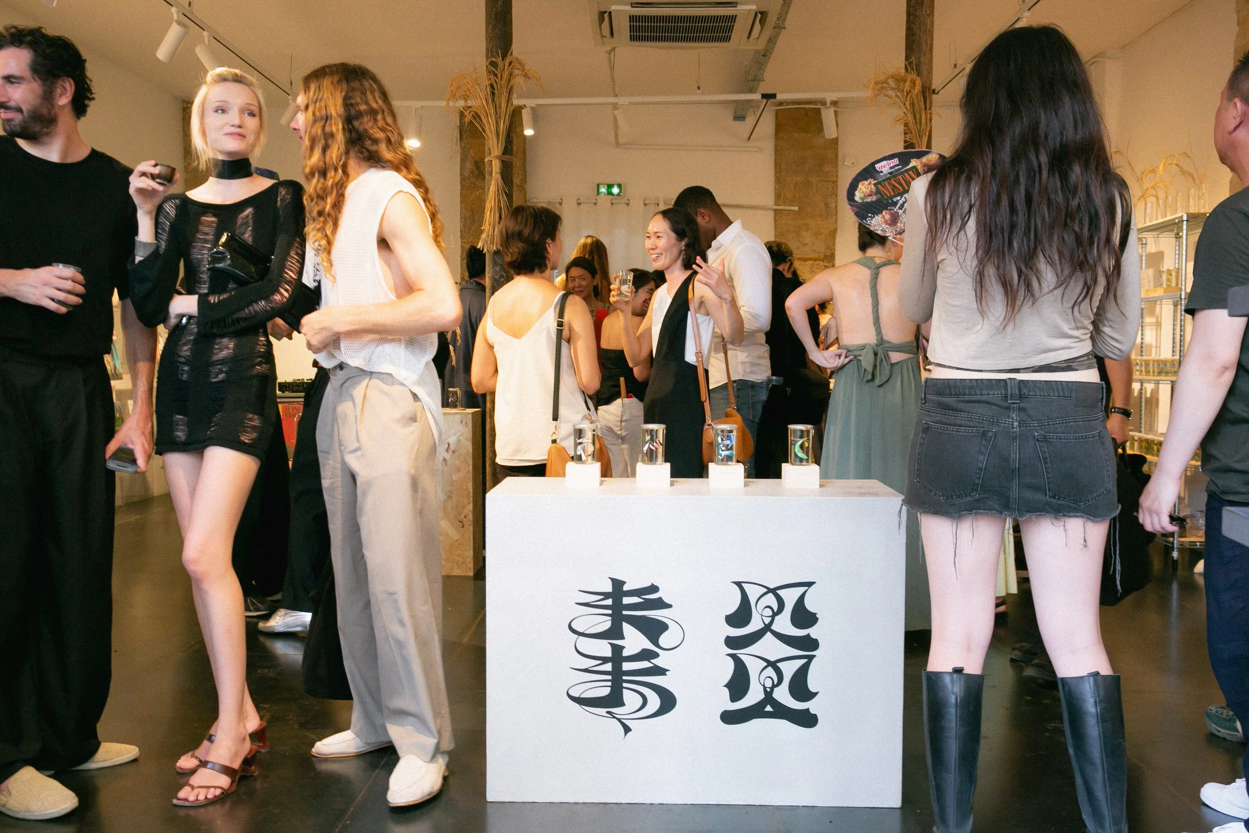 People socializing at an event in an indoor space with a display table with drinks and decorations.