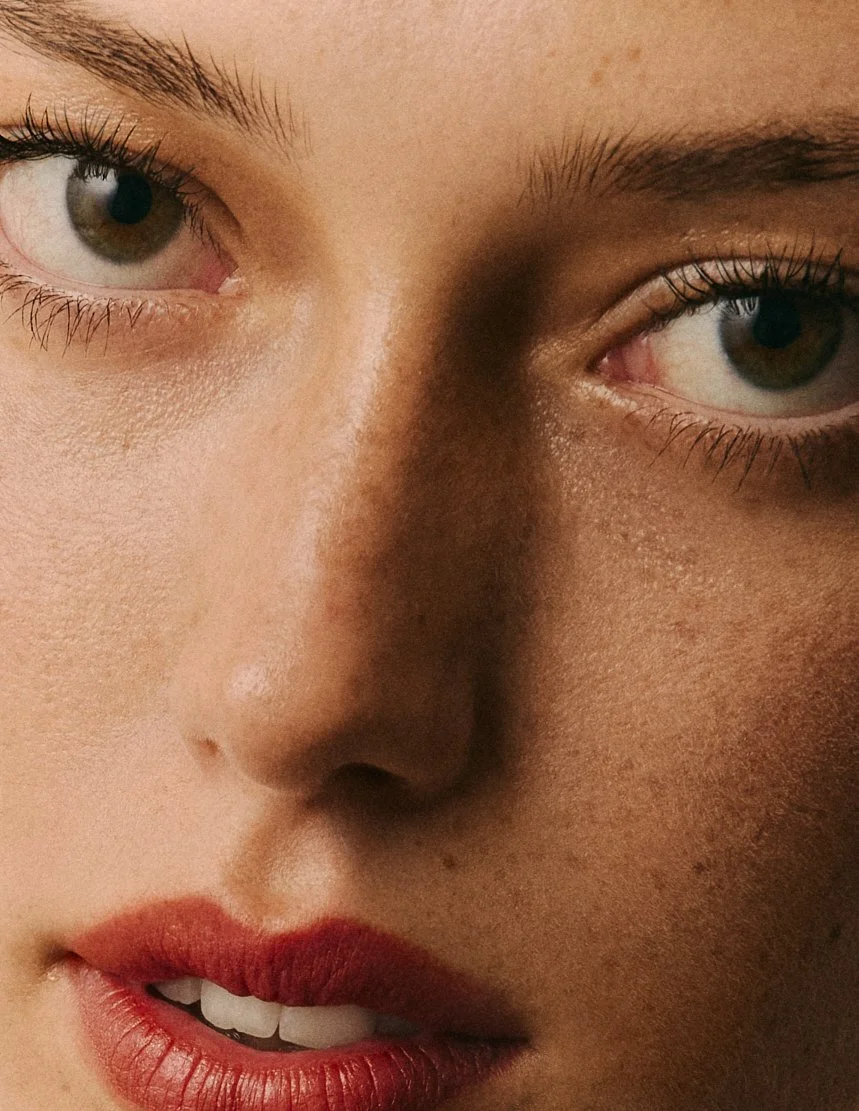 Gros plan du visage d'une femme, montrant ses yeux, son nez et ses lèvres, avec une attention particulière sur ses yeux marron et ses lèvres rouges.