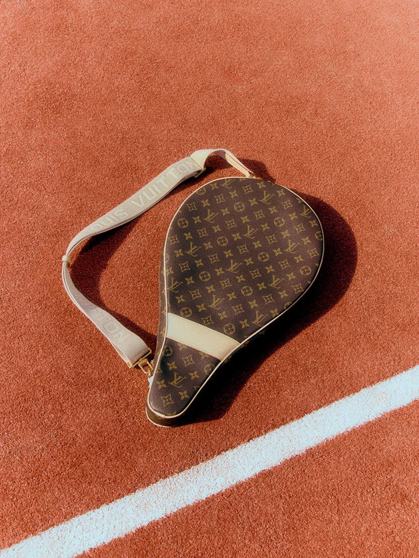 Un objet de sport ressemblant à une raquette de tennis ou de paddle avec un motif Louis Vuitton, placé sur une surface rouge de type piste.