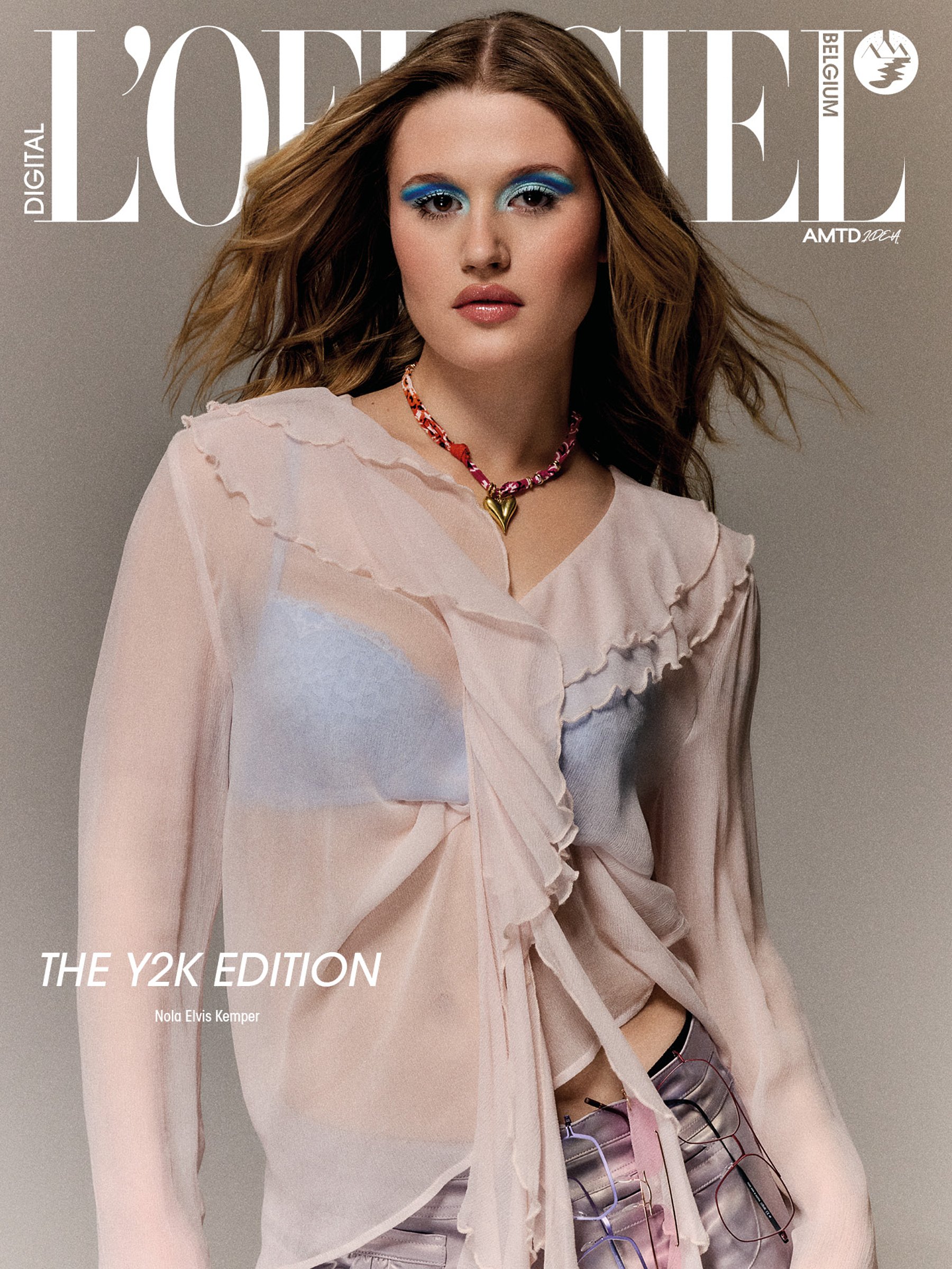 A magazine cover featuring a woman with blue eye makeup, wearing a pink ruffled blouse and pink accessories, and holding multiple pairs of eyeglasses.