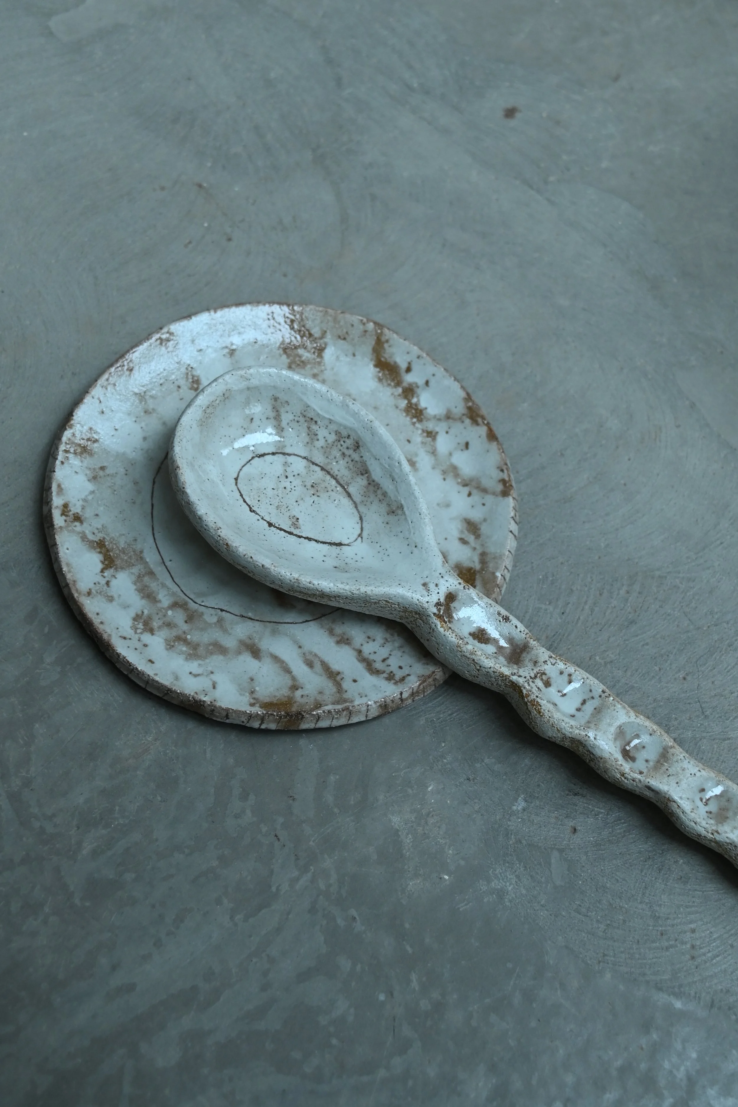 Cuillère de couverts et son repose cuillère réalisé en grès roux au modelage, décor à l'engobe blanche. Réalisé par Jeanne Yaa Stenmanns. 