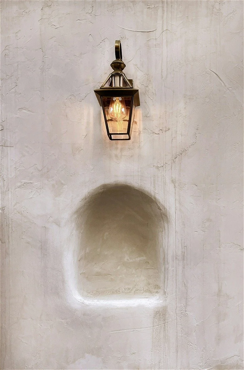 Exterior wall with a mounted lantern light fixture above a recessed niche in the wall.