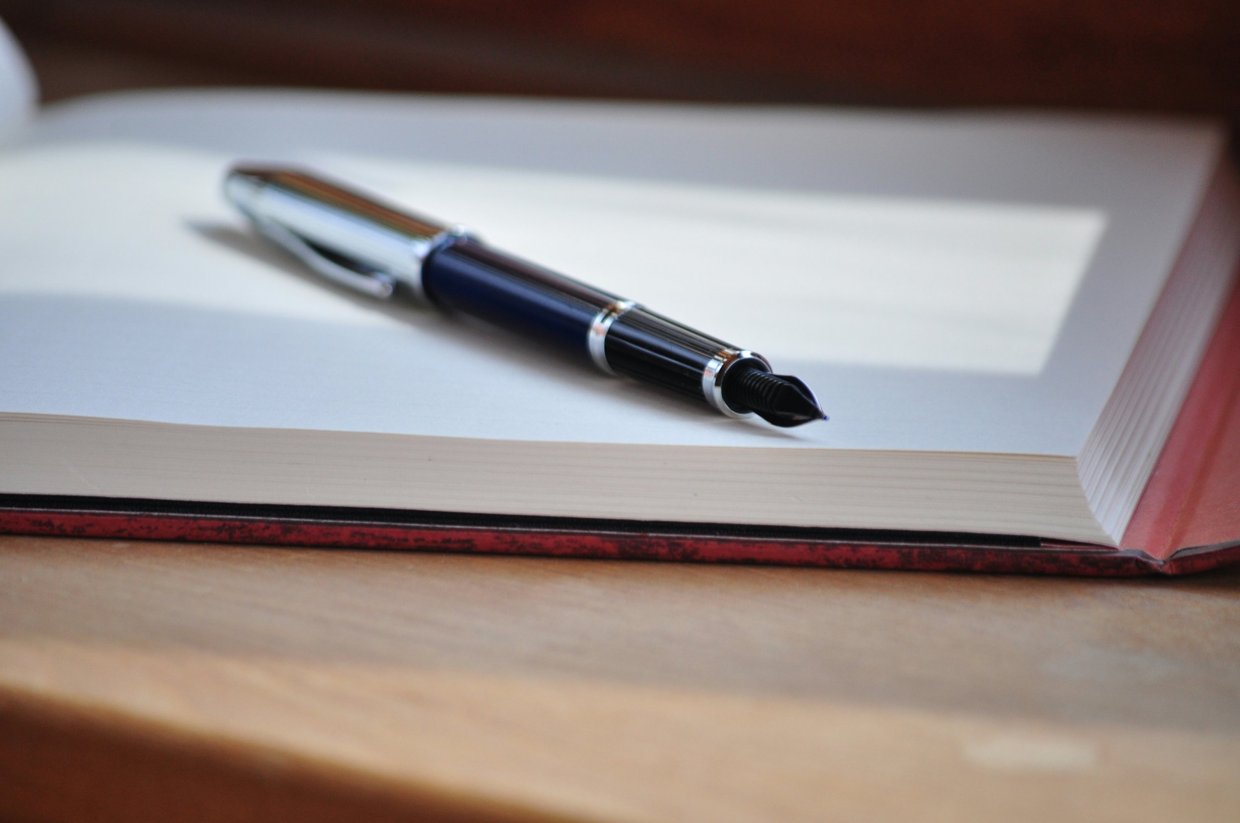 Open notebook with luxury fountain pen in soft light — representing trauma-informed training, reflective practice, and professional mental health workshops at REST