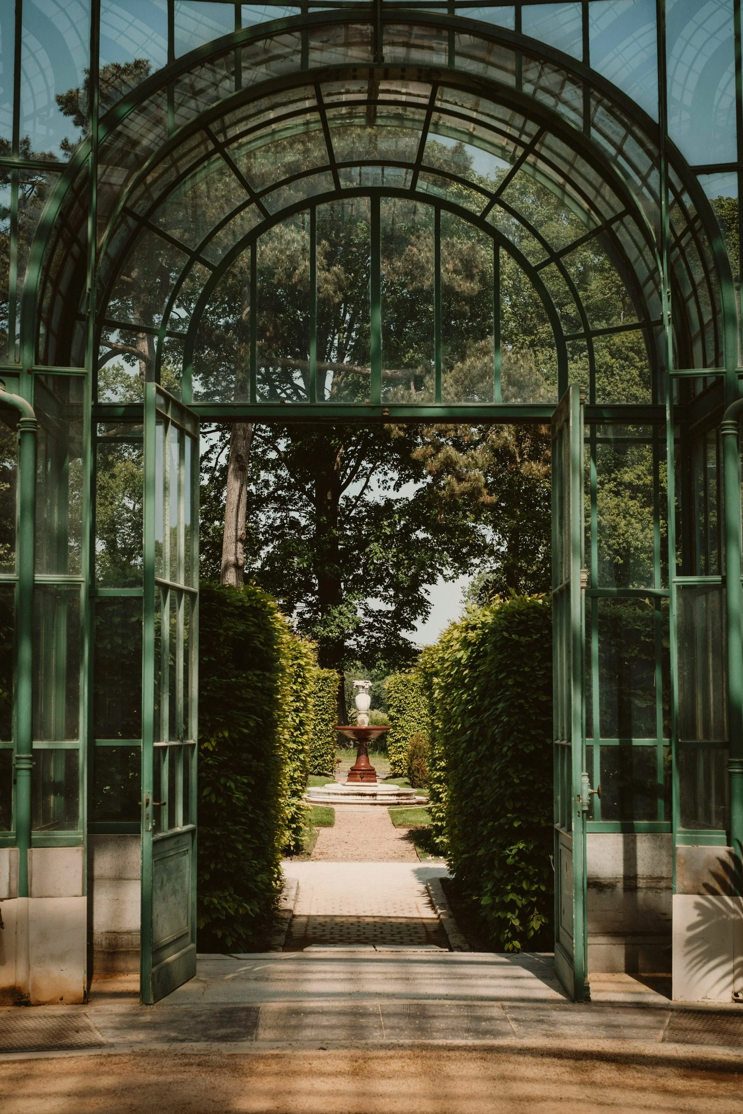 Open glass doors leading to a serene garden path and fountain — representing REST’s online therapy in Nairobi and London, designed to reduce anxiety, build emotional resilience, and help you feel supported.