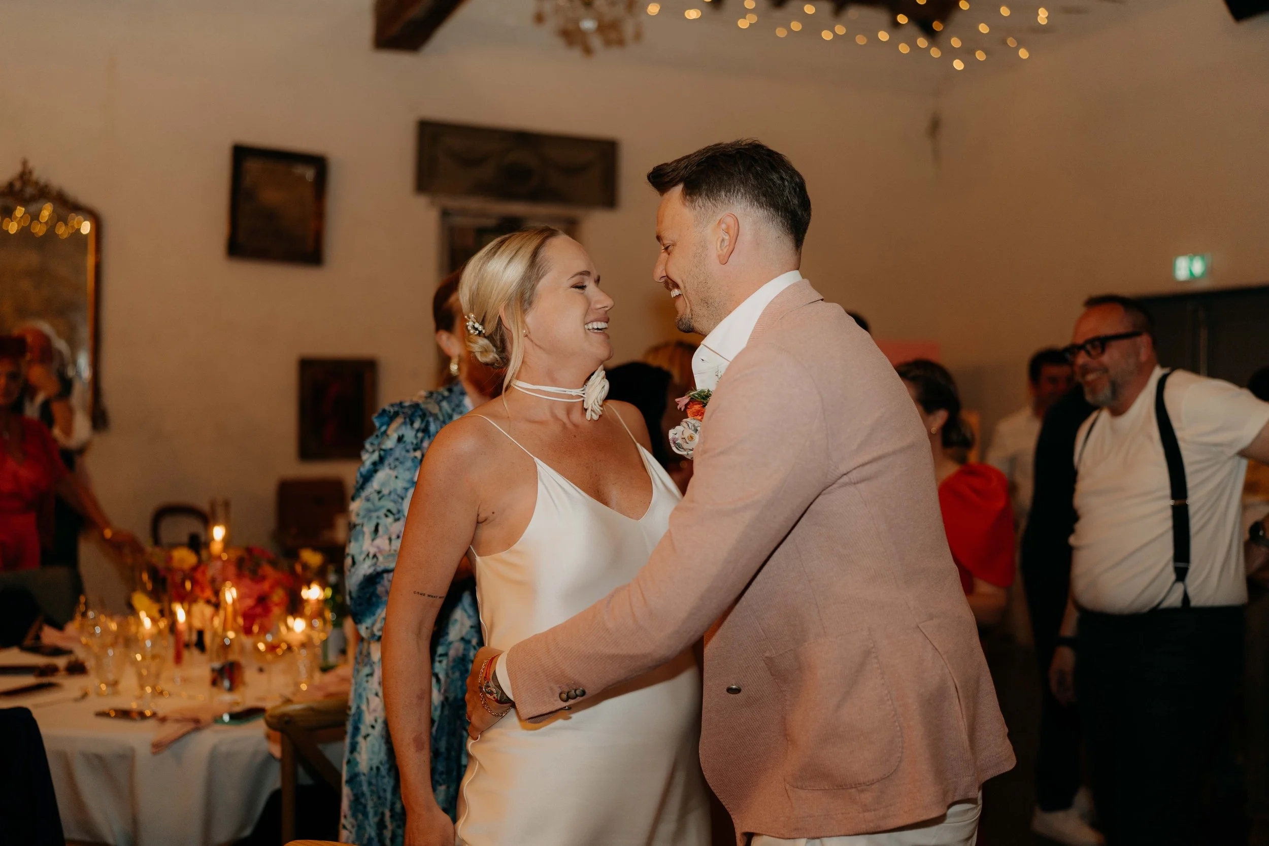 A bride and groom are dancing and smiling at each other during a wedding reception.
