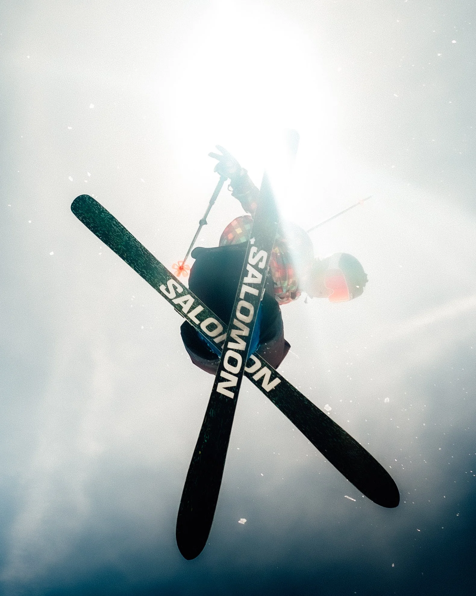 Planche de ski noir avec le texte 'Salomon' sur fond de neige brillante et ciel ensoleillé.