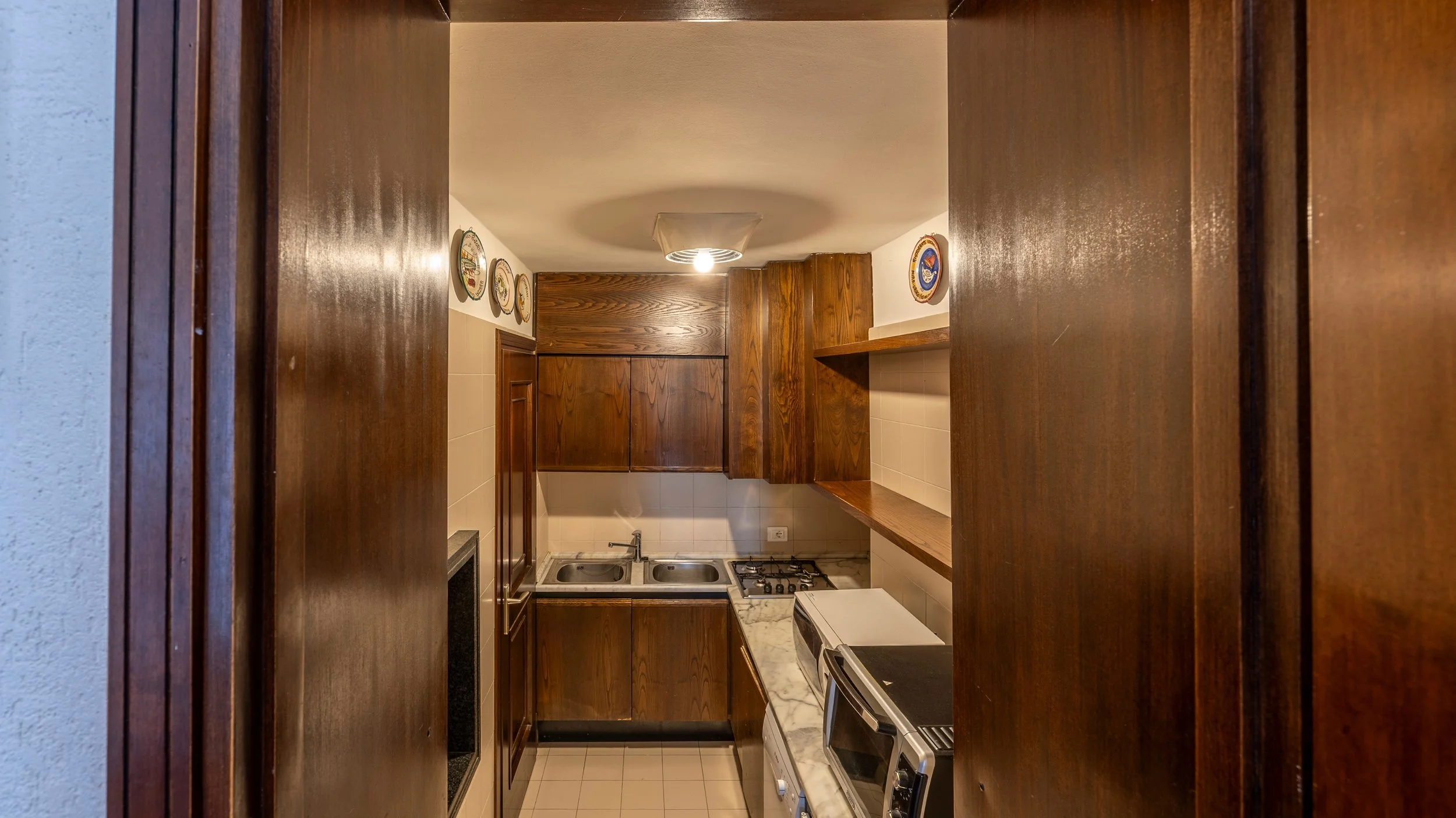 La zona Cucina in legno completa di lavello doppio, piano a gas, microonde, forno, bollitore, macchina caffè Nespresso, Lavastoviglie, frigo.