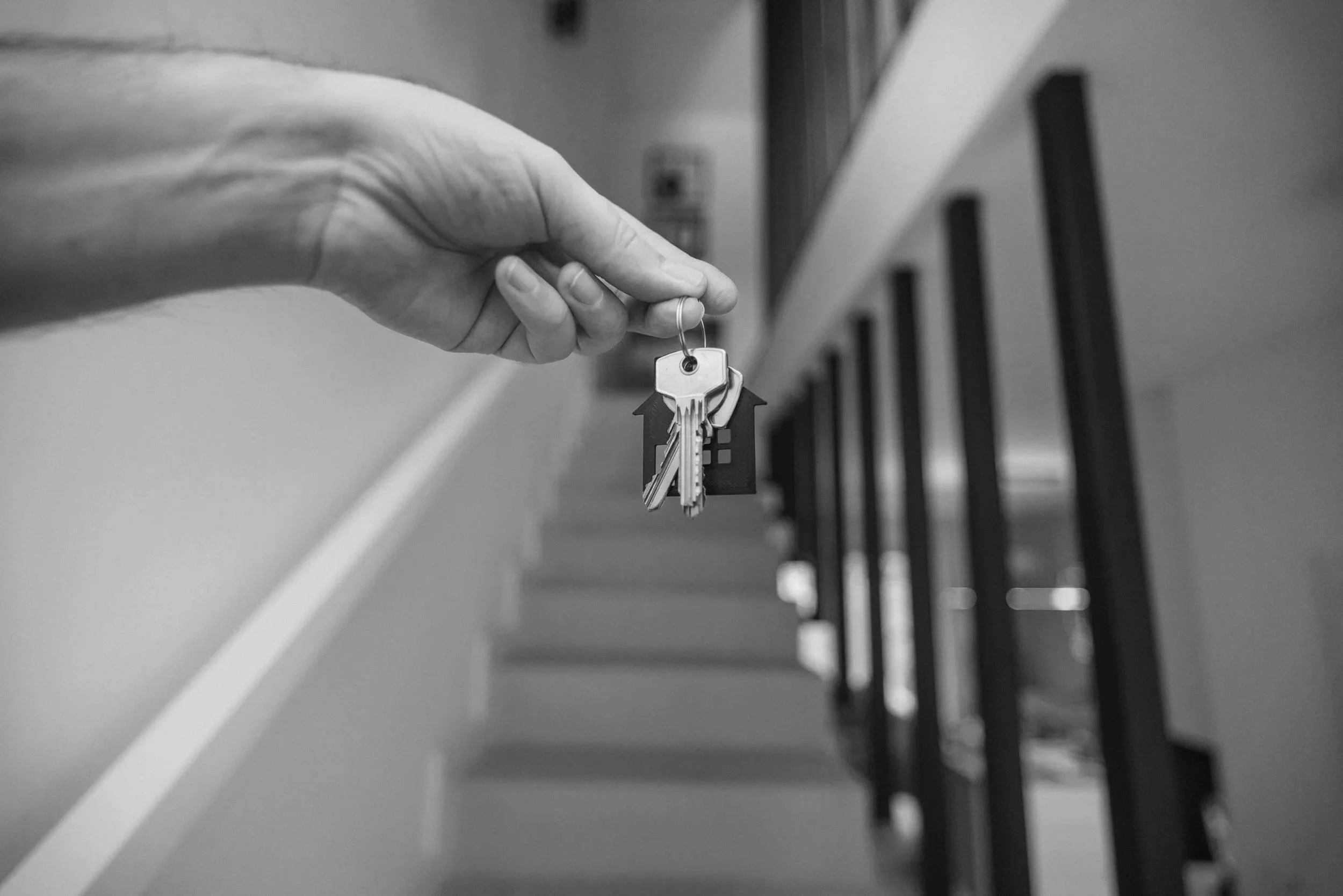 A hand holding a keyring with keys and keychains, approaching a row of mailboxes.