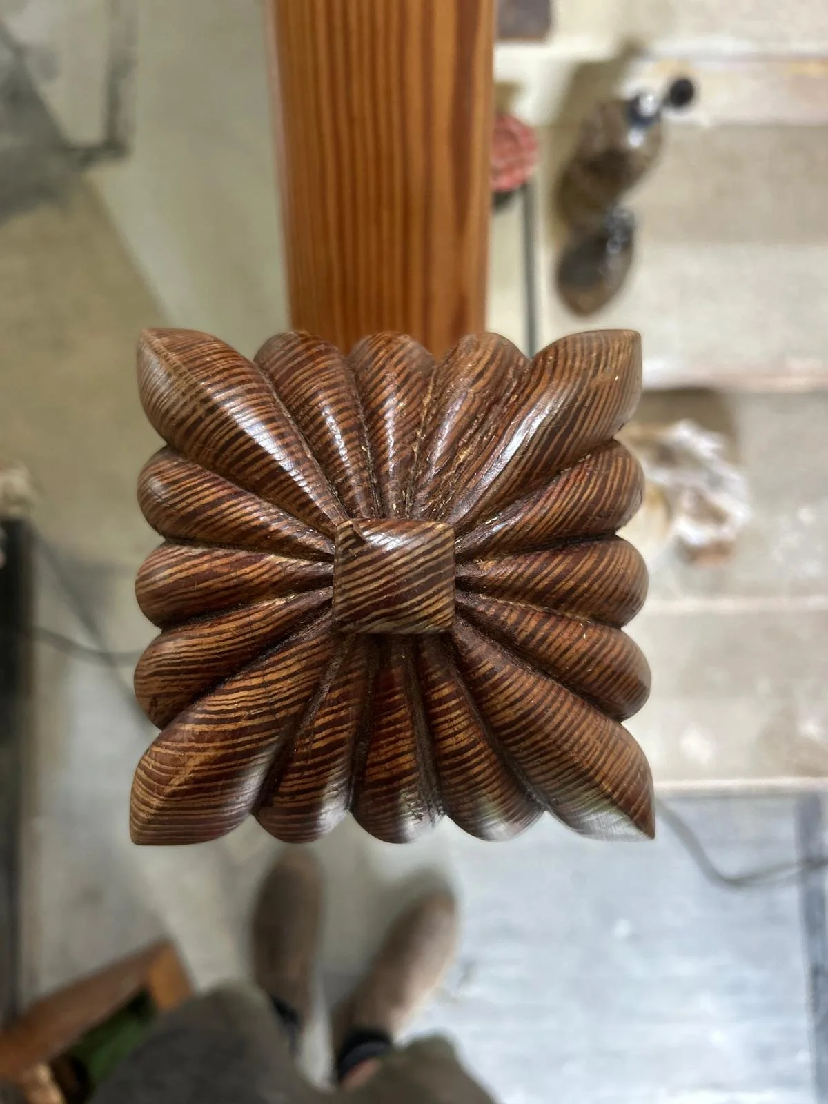 Wooden finial carved in a flower shape with multiple layered petals and a striped pattern.