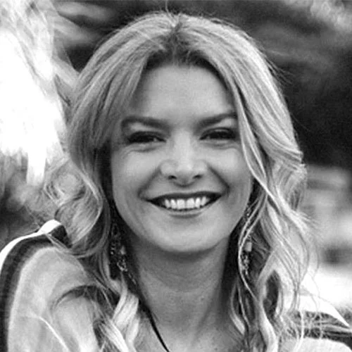 A woman with long, wavy hair smiling in black and white.