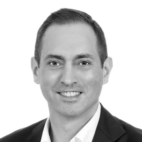 Black and white headshot of a smiling man in a suit and tie.