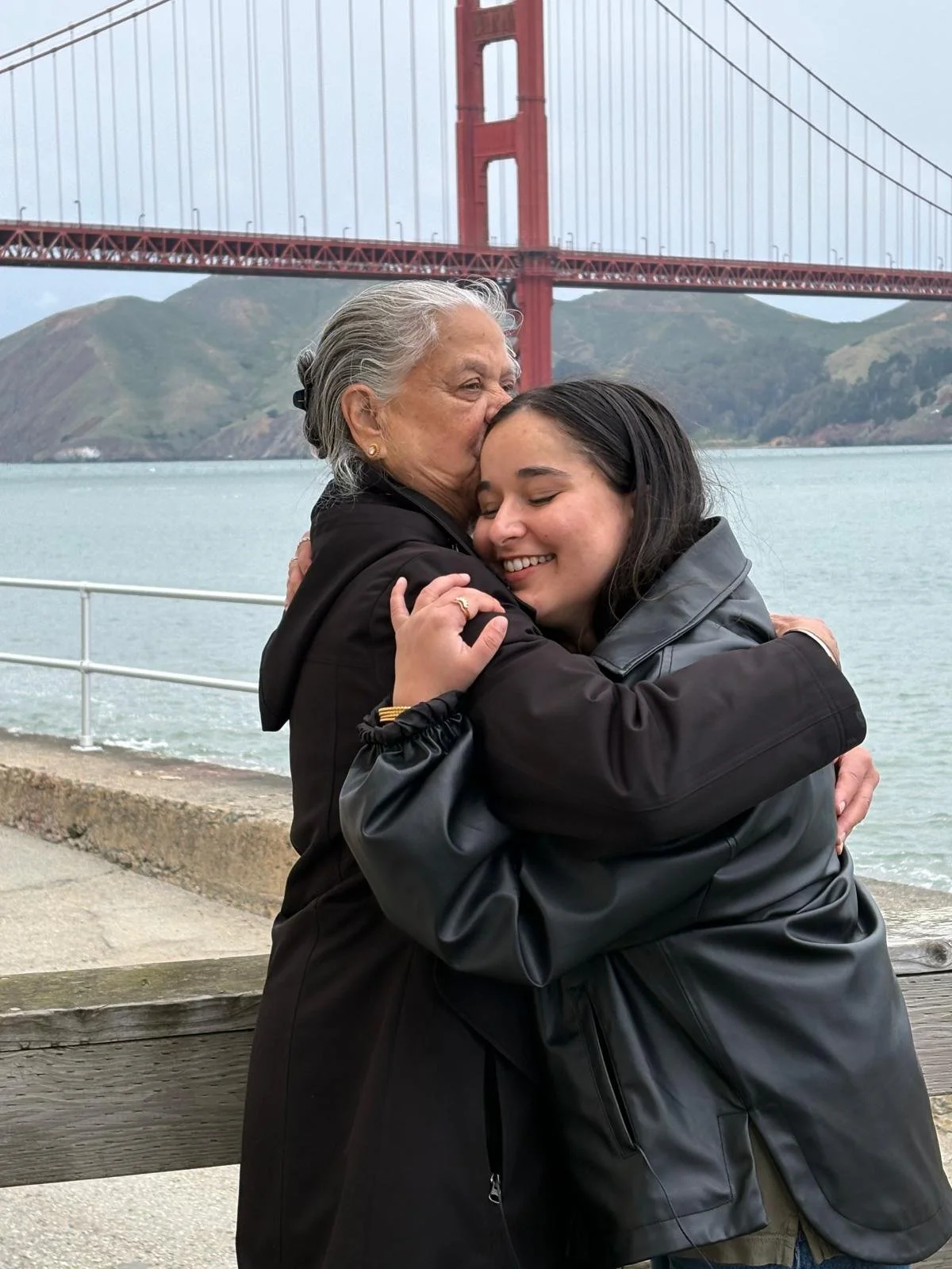Dos mujeres abrazándose con la bahía de San Francisco y el puente Golden Gate de fondo.