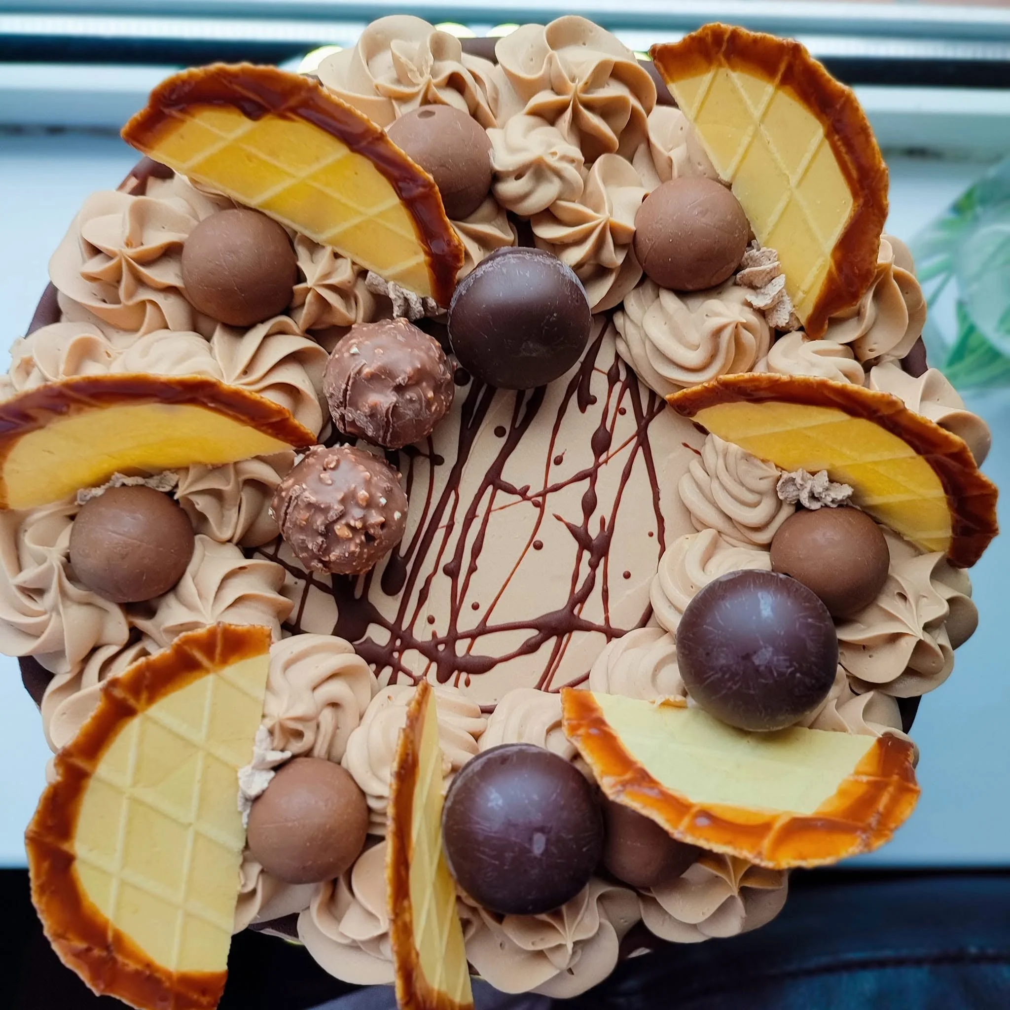 small sized cake decorated with light brown buttercream and various sweets to create a unique look.