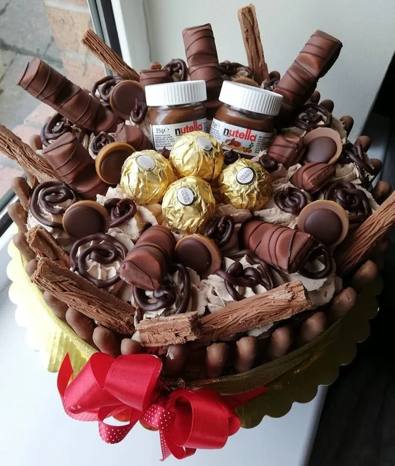 medium sized cake covered in chocolates and more complimentary sweets.