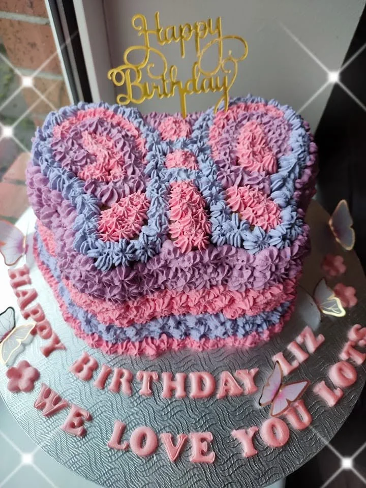 medium sized birthday cake in the shape of a butterfly decorated out of colorful icing.