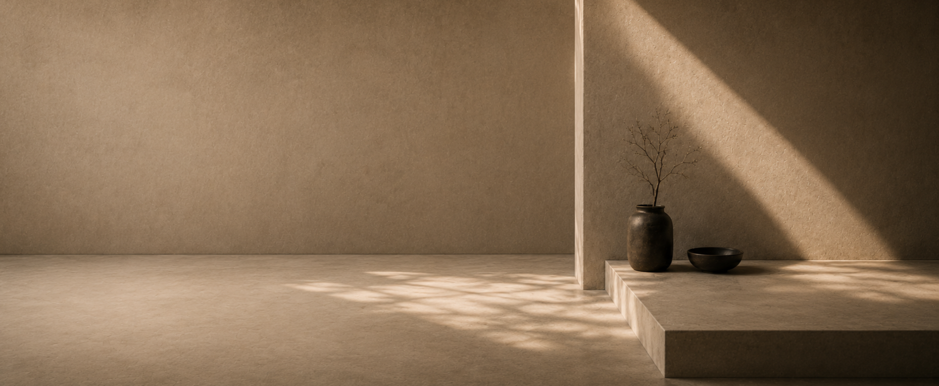 Minimalist scene with a large wall, a tall vase with bare branches, and a small tray, all bathed in soft natural light, creating a calm, serene atmosphere.