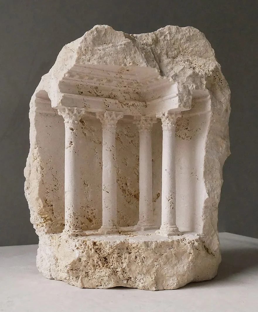 Ancient stone relic with carved columns resembling a small temple or shrine.