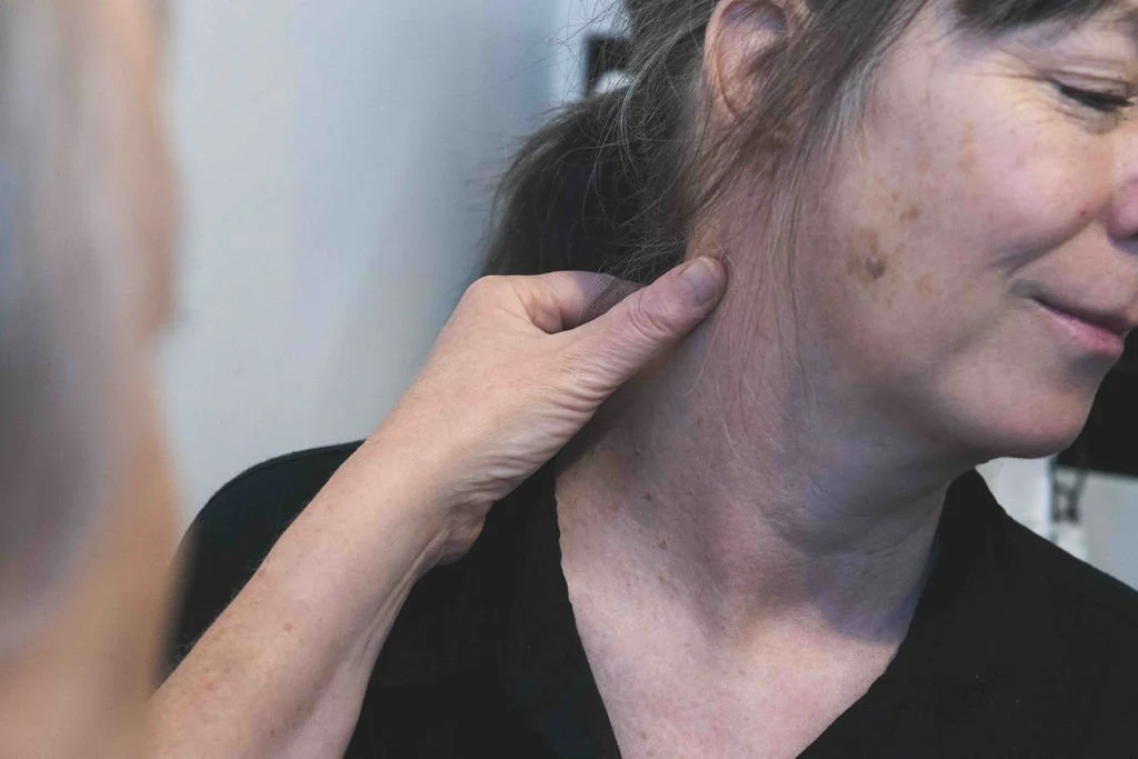 Sarah Hurst examining a seborrhoeic keratosis on a client’s cheek during consultation at her Brighton clinic.