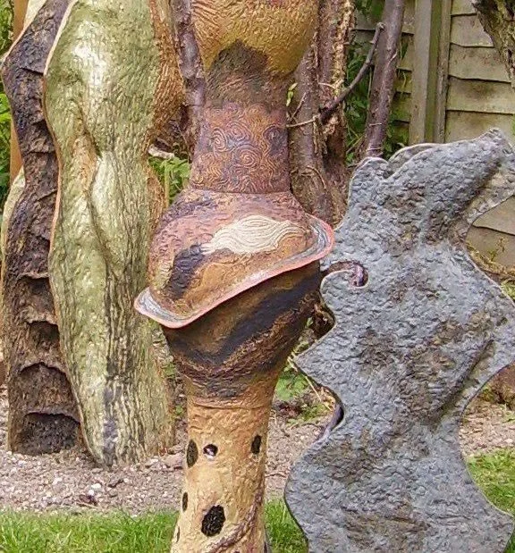 Arts and garden decorations resembling abstract faces and figures in a backyard setting.