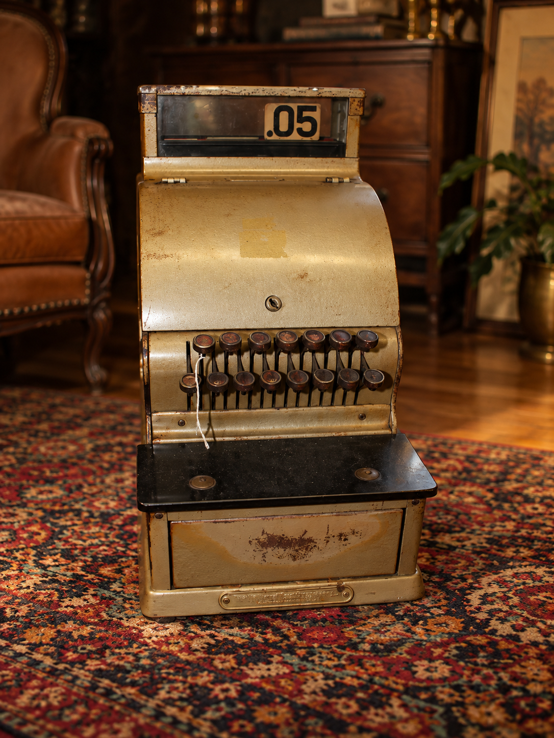 Vintage cash register in a cozy, old-fashioned room with wooden furniture and a patterned rug.