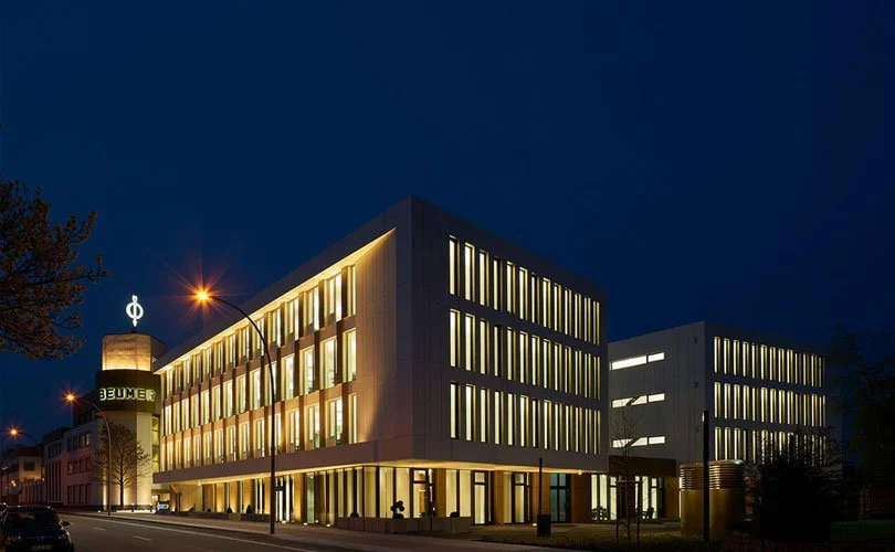 Moderne Bürogebäude bei Nacht mit beleuchteten Fenstern und Straßenlaternen