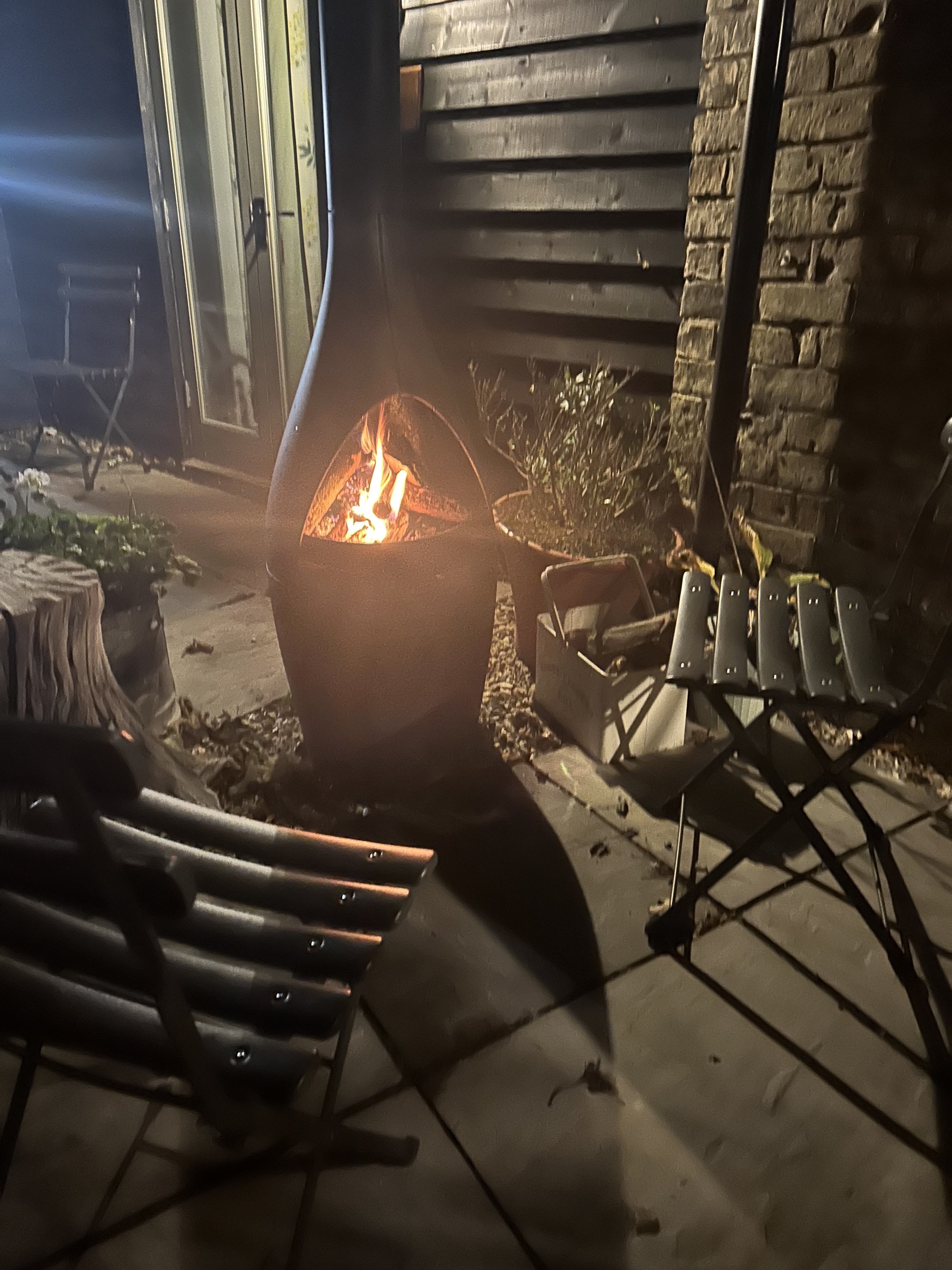 A private Morso outdoor fireplace on a wooden patio at Bridleway Lincolnshire, set up with blankets, a hot chocolate maker, and marshmallows for toasting.