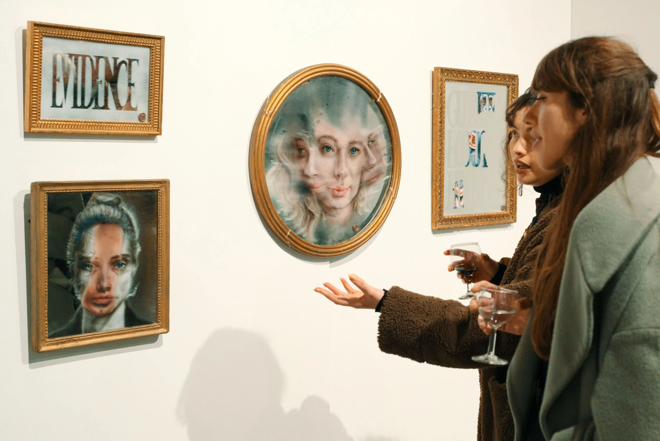 Groupe de personnes regardant des œuvres d'art dans une galerie, échangeant des discussions et tenant des verres de vin.