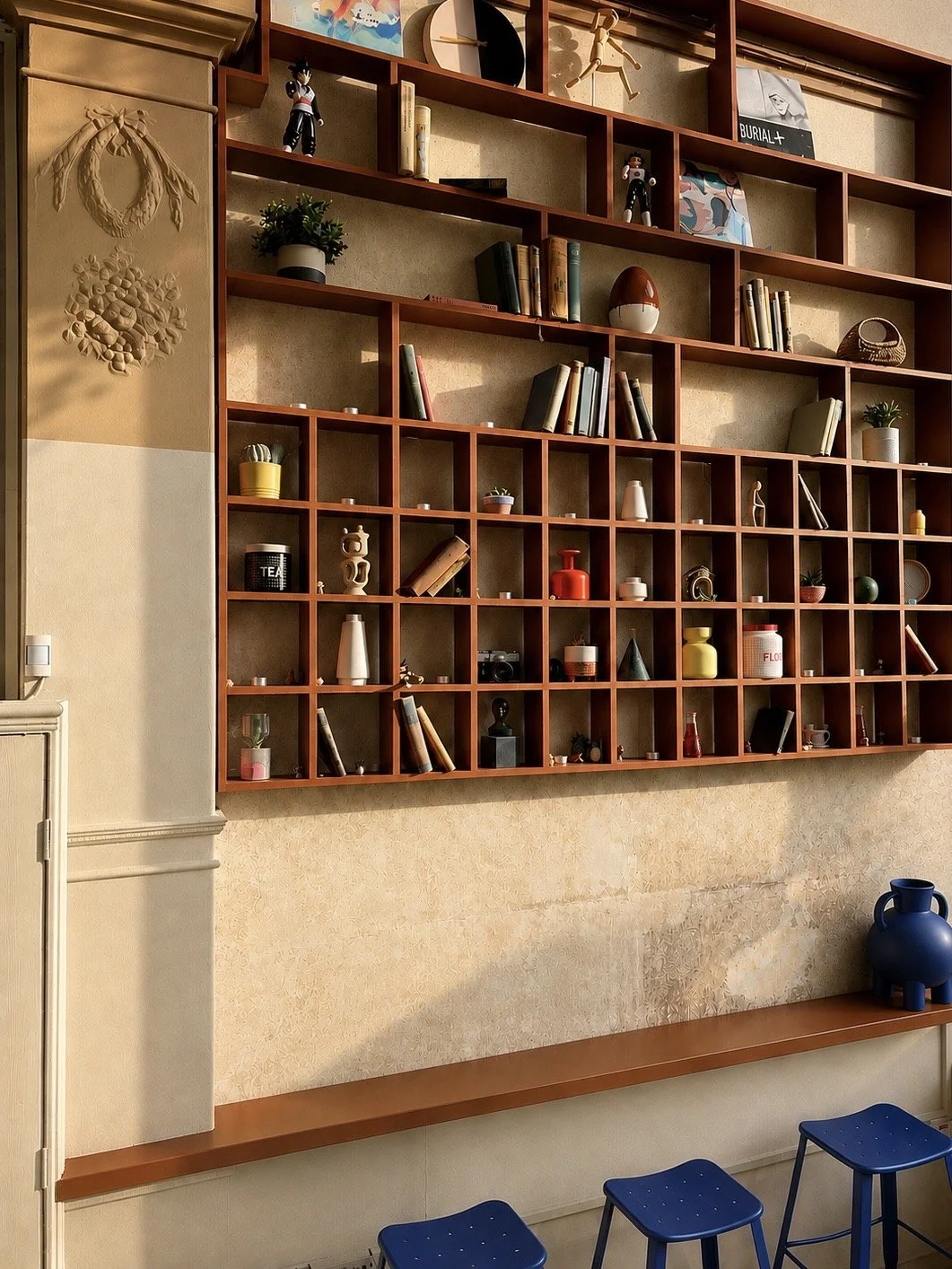 Wooden wall shelf with various decorative items, books, small plants, and figurines, above a wooden ledge with blue stools in a cozy room.