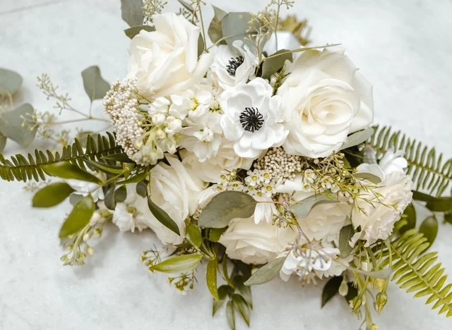 White floral bouquet with roses, anemones, and greenery.