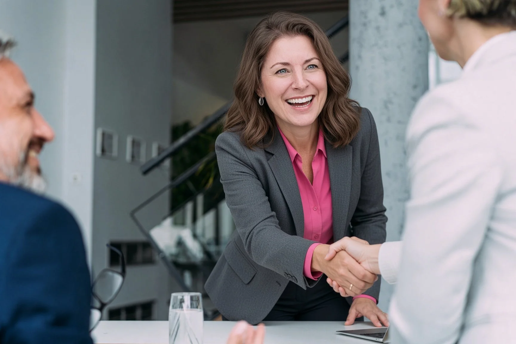 Rebecca Salt shaking hands with another woman in a white blazer, both smiling, in a professional setting.