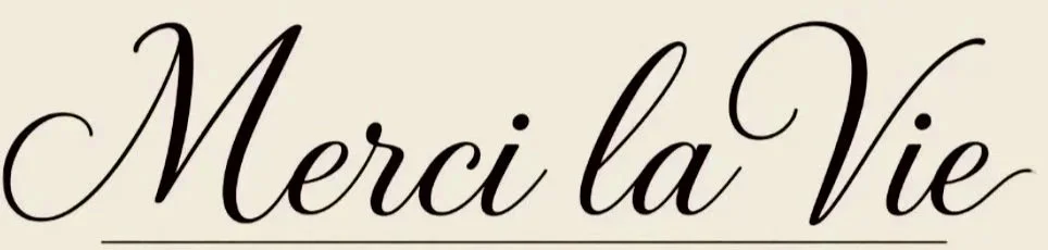 Elegant script text that reads "Merci la Vie" on a light beige background.