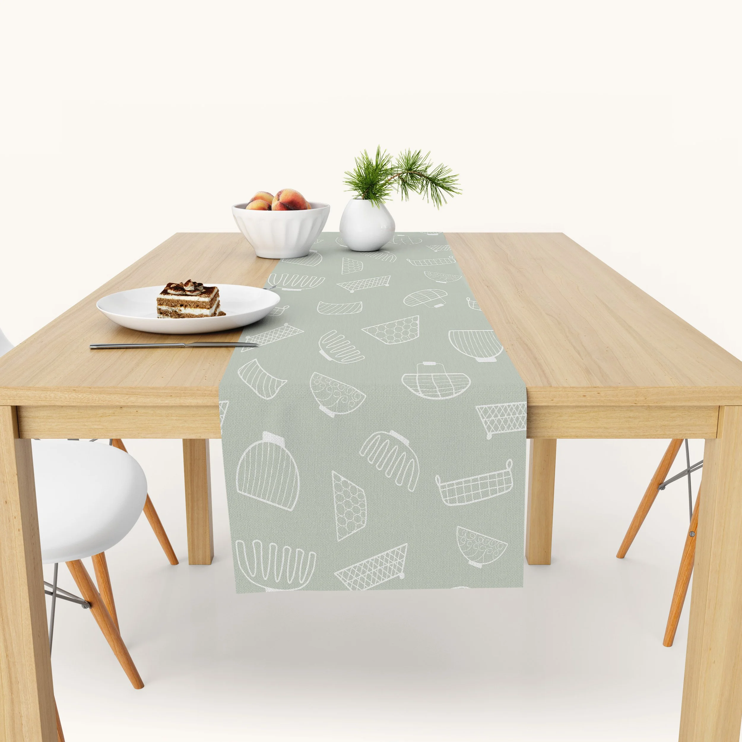 Sage green table runner with hand drawn white wire baskets on a light wood dining table.